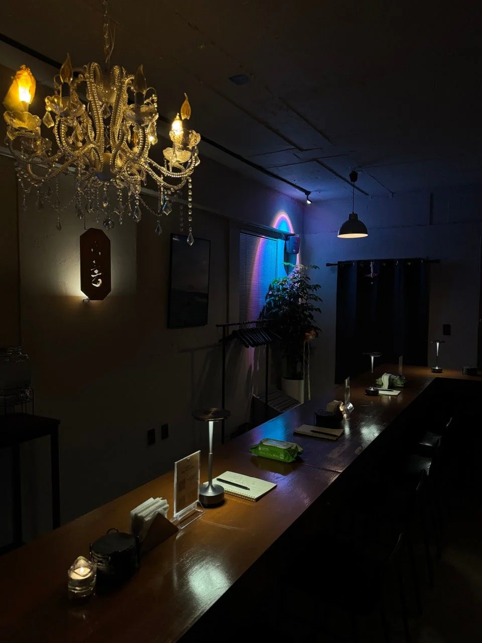 Jeju Ahop 江南店的長吧台,水晶吊燈亮著,牆上映著藍色與粉紅色的霓虹光